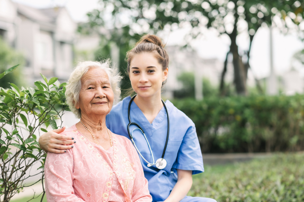Nurse assisting a senior in a wheelchair outdoors